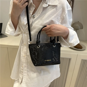 Chic black snake-patterned bucket bag with gold lettering shown on a fashion model