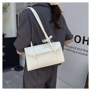 Detail of cream white shoulder bag featuring an elegant ribbon bow on the strap