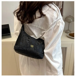 Détail du sac hobo noir à motif serpent montrant le logo métallique et le similicuir brillant