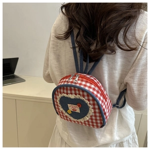 Close-up of red and white checkered mini backpack with lace heart patch on model