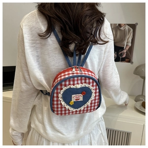 Gros plan d'un mini sac à dos vichy rouge et blanc avec patch cœur et motif cerise