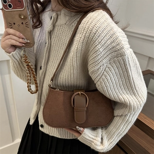 Brown suede underarm bag with gold buckle shown on a model in a retro style