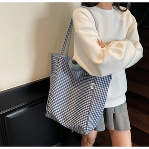Detail of blue and white checkered tote bag featuring a fashion woven label and large capacity