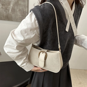 Minimalist beige canvas baguette bag with large bronze ring buckle and slim shoulder strap