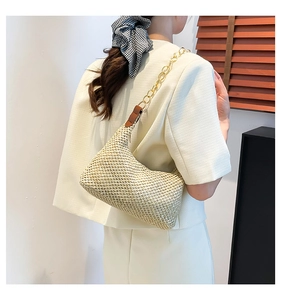 Detail of woven straw shoulder bag with elegant thick golden acrylic chain strap