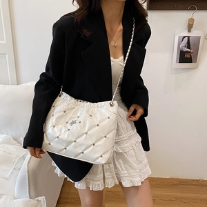 White quilted crossbody bag with studs and star detail worn on shoulder in studio