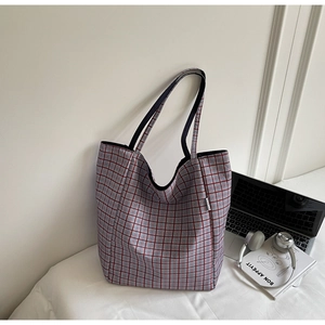 Detail view of plaid tote bag featuring red and blue patterns with black shoulder straps