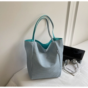 Detail of blue and white checkered canvas tote bag with bright blue lining and side label