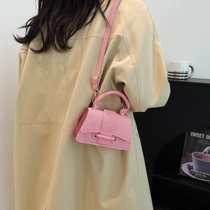 Pink hourglass crossbody bag with textured finish shown on a model in trench coat