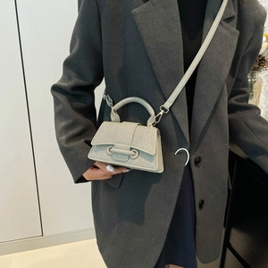 Chic light gray hourglass handbag with top handle and strap styled on a gray blazer