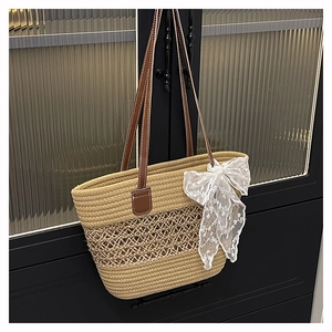 Detail of woven straw tote bag featuring mesh hollow pattern and white lace bow accessory