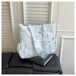 Detail of mint green plaid tote bag featuring a translucent front zipper pocket and side pockets