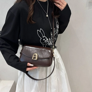 Petit sac bandoulière en cuir marron foncé avec fermoir doré porté par un mannequin