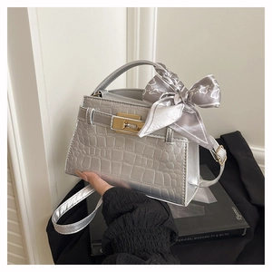 Detailed close-up of silver crocodile pattern bag with metallic twist lock and silk scarf