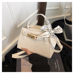 Detail view of white crocodile embossed mini square bag with golden twist lock and silk scarf