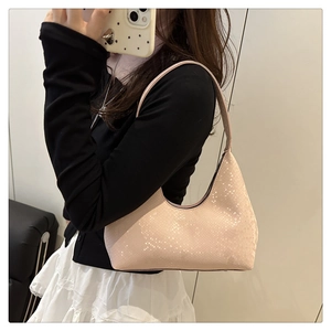 Detail of snake skin texture and metal zipper on a pale pink semi-circle hobo bag