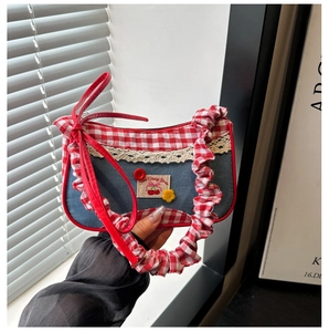 Detail of denim and red plaid shoulder bag with lace trim and cherry patch embellishment