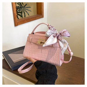 Pink croc-embossed handbag detail with silk scarf handle and golden clasp