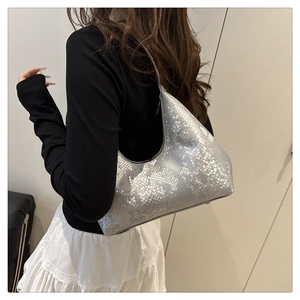 Detail of silver snake-patterned underarm bag showing texture and shoulder fit on model