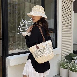 Beige straw tote bag with white lace bow and matching sun hat for summer beach vacations