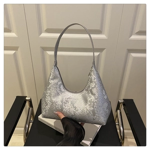 Macro view of metallic silver snakeskin texture on a crescent-shaped hobo handbag