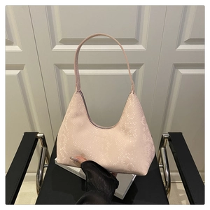 Close-up of light pink snakeskin embossed shoulder bag held against a minimal background