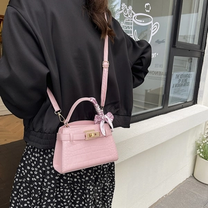 Pink crocodile pattern handbag with decorative silk scarf on outdoor model cross-body style