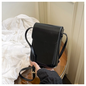 Detail of glossy black PU leather flap bag with gold adjustable metal buckle and slim strap