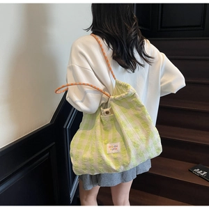 Detail of checkered tote bag with woven rope handle and woven brand patch in green and white