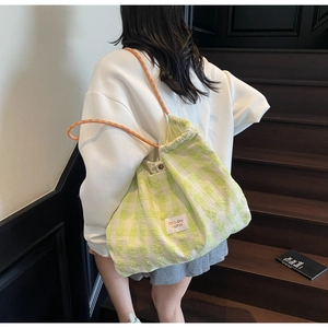 Detail of green checkered canvas tote with woven rope straps and drawstring closure