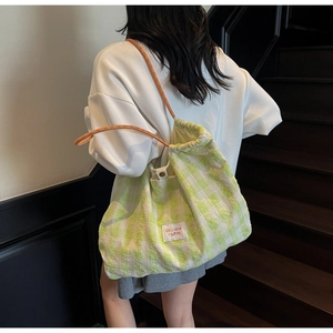 Detail of green checkerboard canvas tote with drawstring and orange polka dot rope