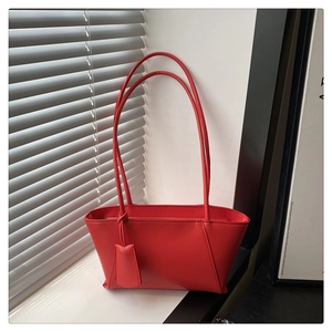 Detail view of red minimalist underarm bag with slim shoulder strap and leather tag