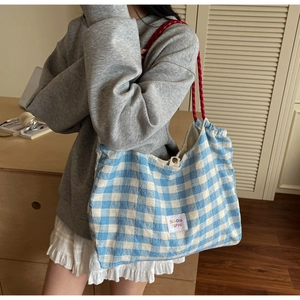 Detail of blue checkerboard canvas tote bag with red rope straps and text label