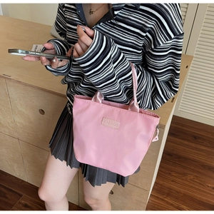 Dettaglio borsa a secchiello in nylon rosa con toppa in pelle FASHION in mano al modello