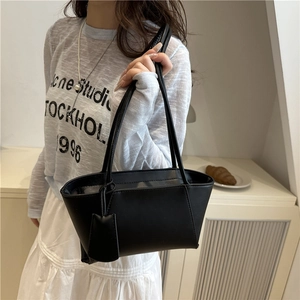 Minimalist black rectangular shoulder bag with slim straps and a decorative hangtag