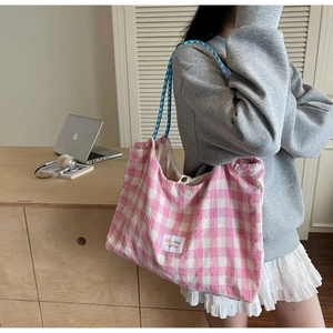 Detail of pink plaid tote bag with decorative blue rope handle and brand label
