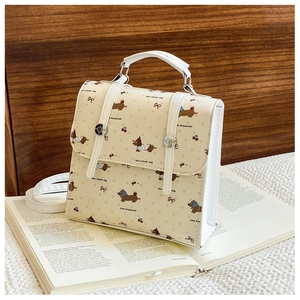 Detail of cartoon puppy and cherry print on a yellow square bag with white leather piping