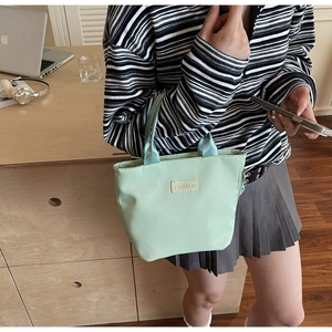 Dettaglio della borsa tote in nylon verde menta con patch fashion in un set lifestyle