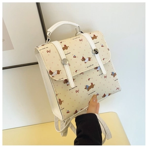 Close-up of cream PU backpack with dachshund and cherry prints held by hand