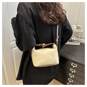 Détail du sac bandoulière crème à rayures verticales avec finitions en cuir marron