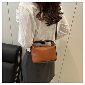 Détail du sac à bandoulière marron avec texture rayée verticale et garnitures dorées chic