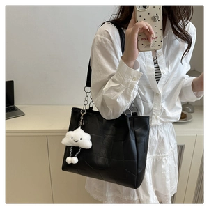 Detailed view of black patchwork leather shoulder bag with plush cloud charm accessory