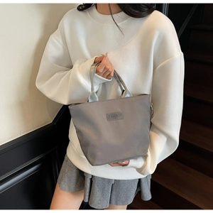 Foto lifestyle di una borsa a mano grigia in nylon con dettaglio patch Fashion trendy