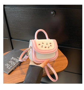 Détail du sac bandoulière rose avec imprimé cerise et surpiqûres sur table en bois