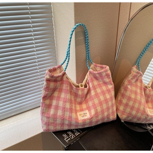 Close-up of pink and white plaid tote bag with blue knotted handles and metal snap closure