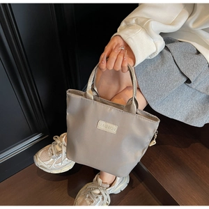 Dettaglio di una borsa in nylon grigio con etichetta FASHION su fondo in legno