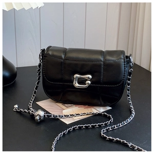 Close-up of black quilted saddle bag featuring silver metallic buckle and chain strap