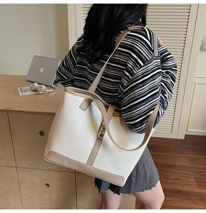 Detail of color-block tote bag featuring a gold metal twist lock and brown leather trim