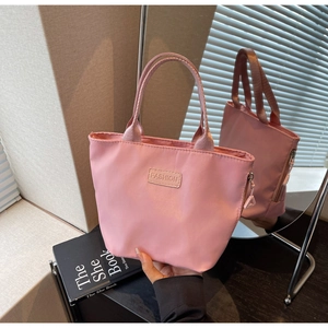 Dettaglio della borsa a secchiello in nylon rosa con etichetta FASHION e cerniera in metallo