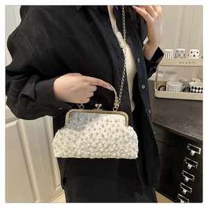 Detailed close-up of white floral lace texture and pearl embellishments on the small box bag